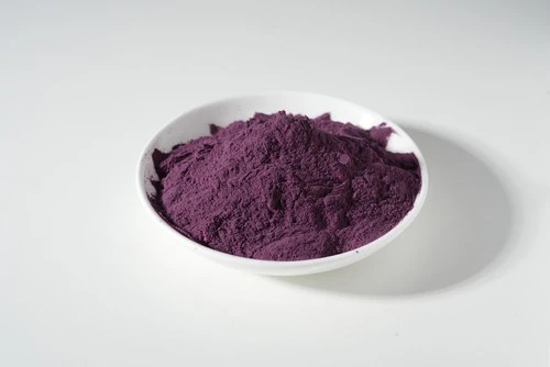 Deep purple milled botanical powder presented in a white dish